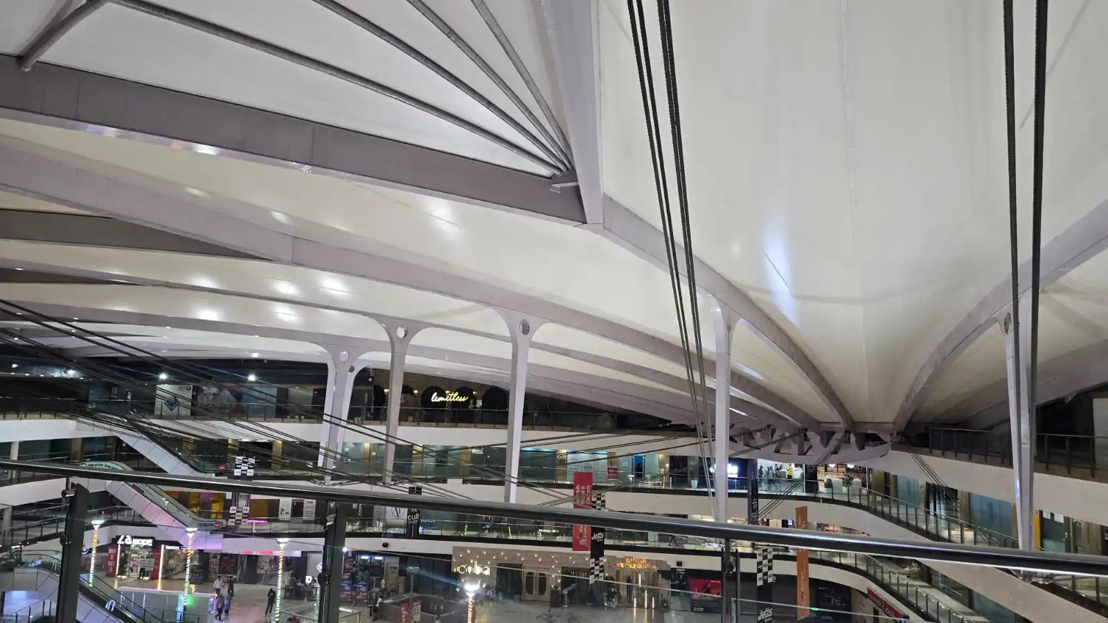 Vasant Square Mall Vasant Kunj — low-angle view of the membrane perimeter and tree-form support columns above the multi-level concourse, Ekra Decor